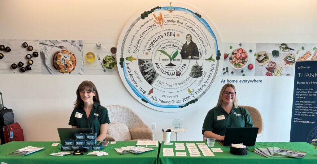 Two Reach staff members wearing green client polos sit at a table.